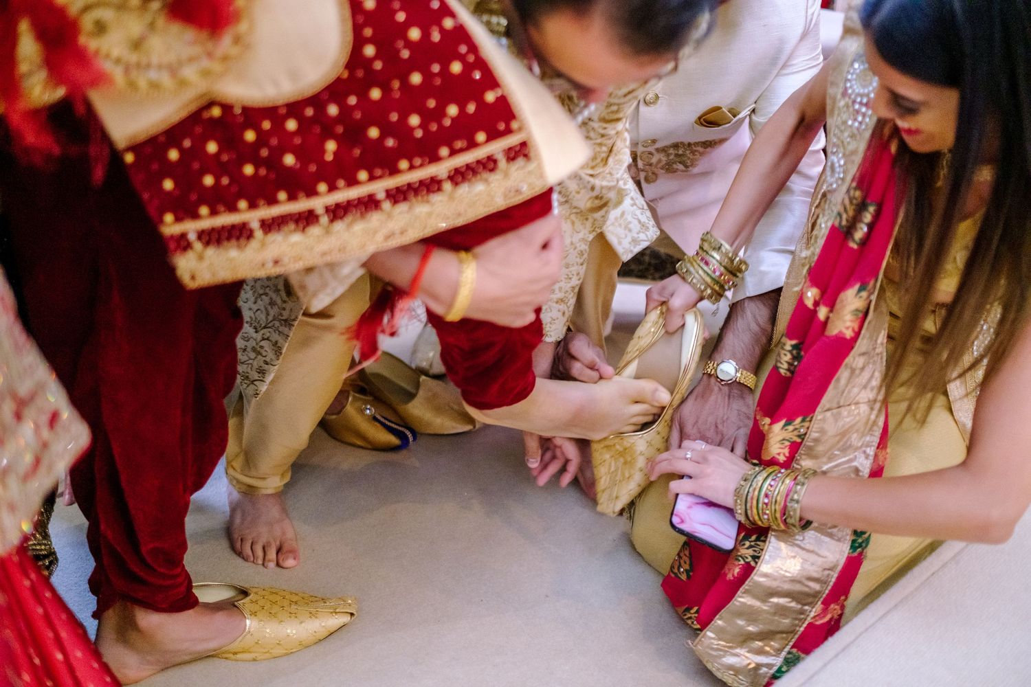 Close-up of traditional Indian wedding ritual showing detailed embroidered clothing and ceremonial elements.