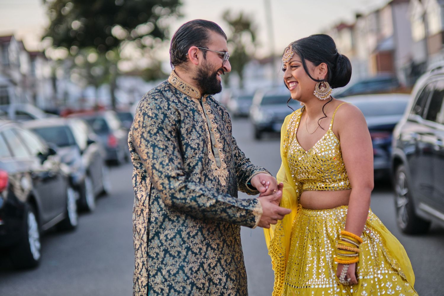 A couple in matching outfits shares romantic moments during a sunset photoshoot on a city street.