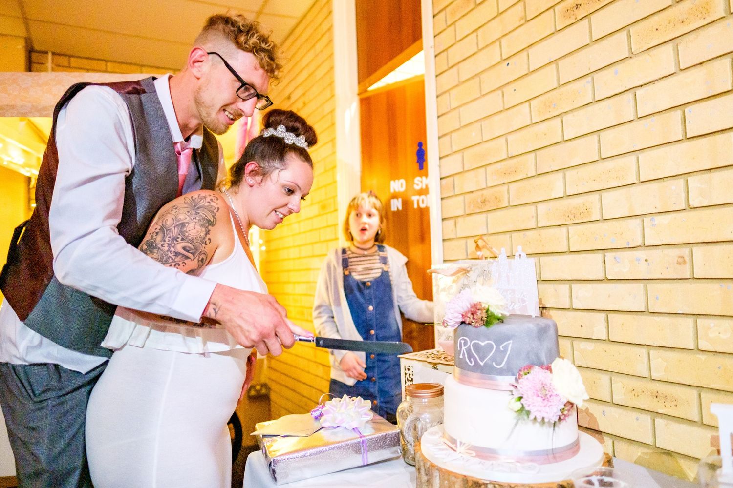 Wedding couple cutting their elegant white tiered cake together at an outdoor reception.