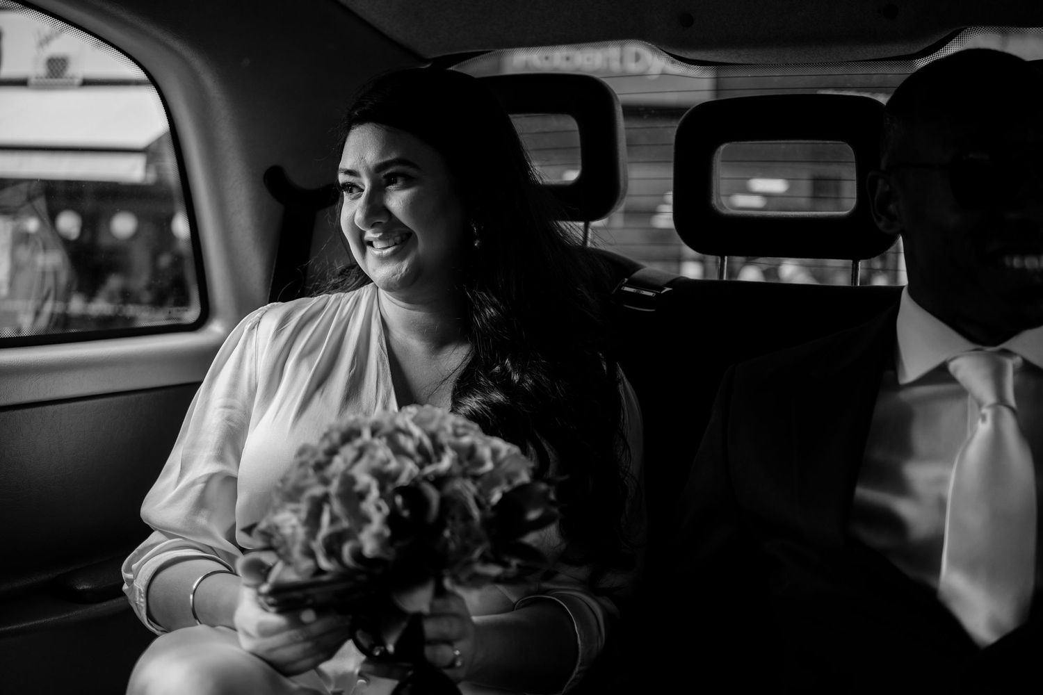 Black and white photo of wedding preparations in a car with elegant details.