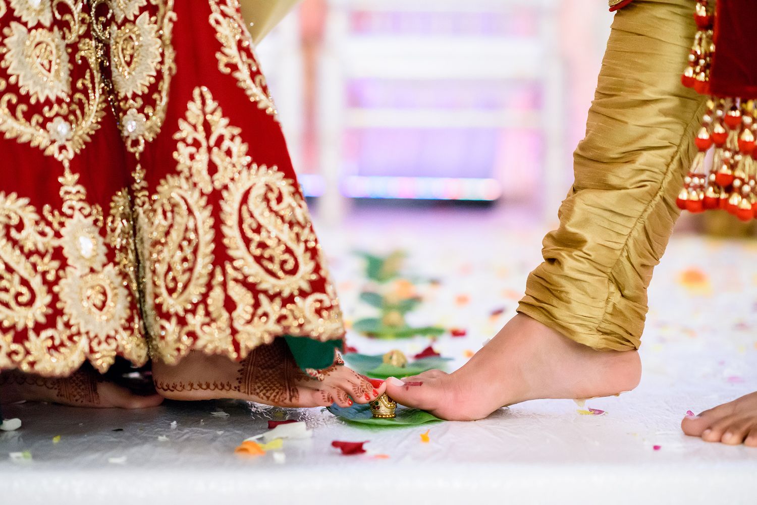 Close-up of feet surrounded by scattered rose petals at an Indian wedding ceremony.