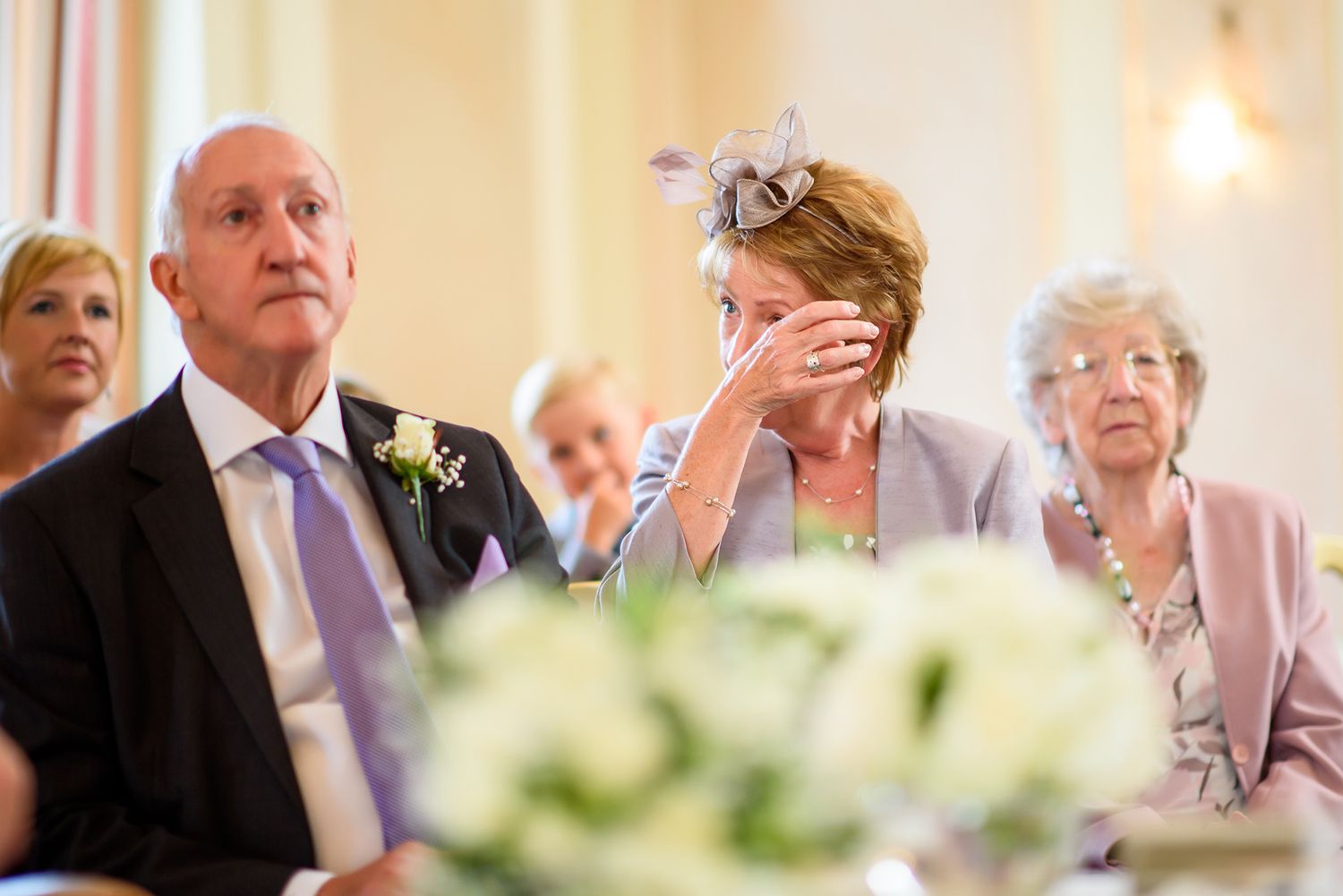 Wedding guests enjoy speeches during an elegant indoor reception.