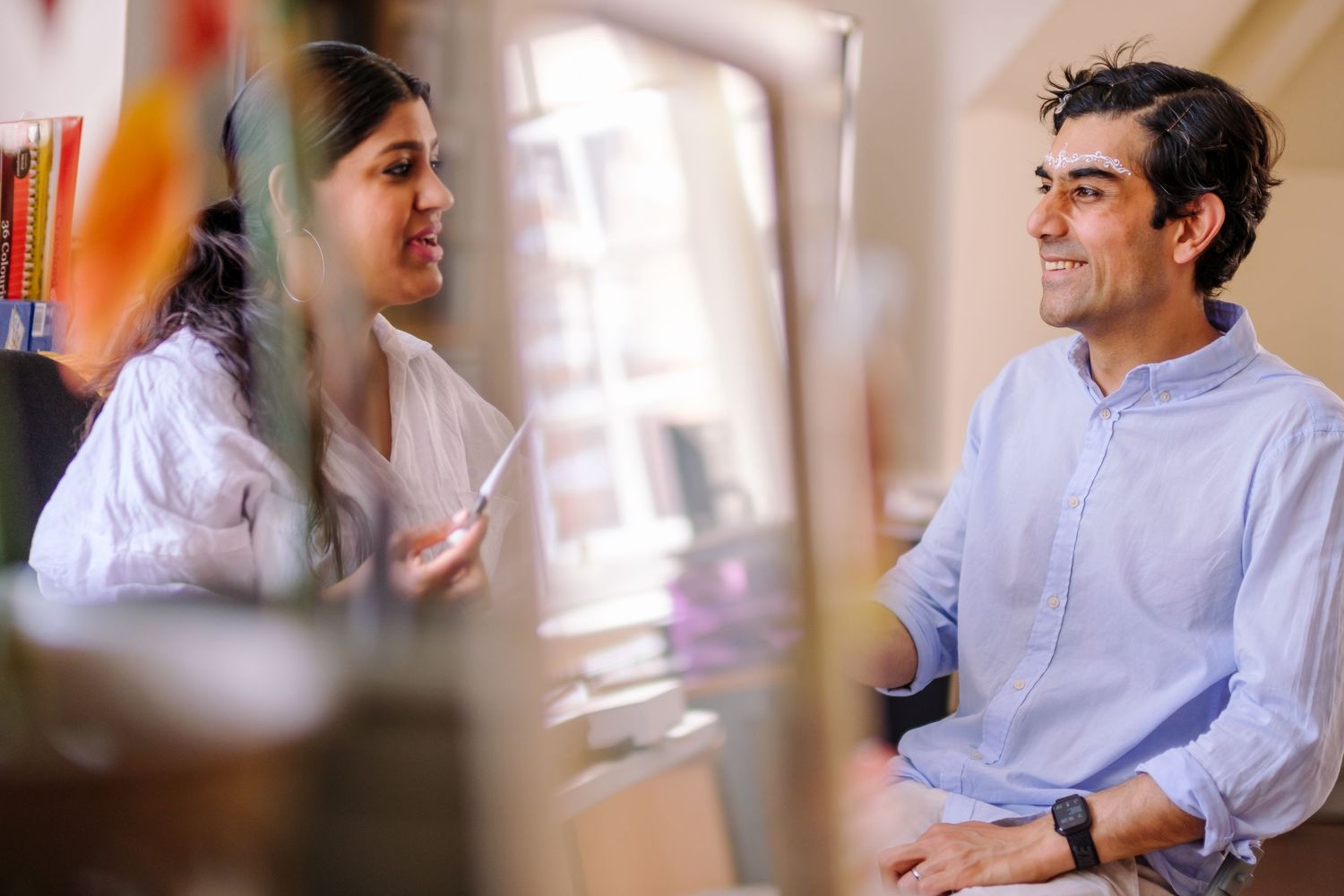 Person in light colored shirt sitting at desk while gesturing during conversation.