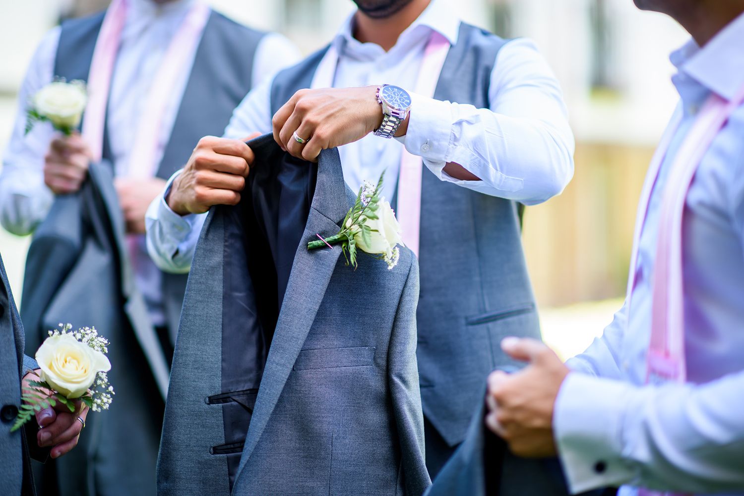 Wedding party members in blue suits and white shirts gather outdoors.
