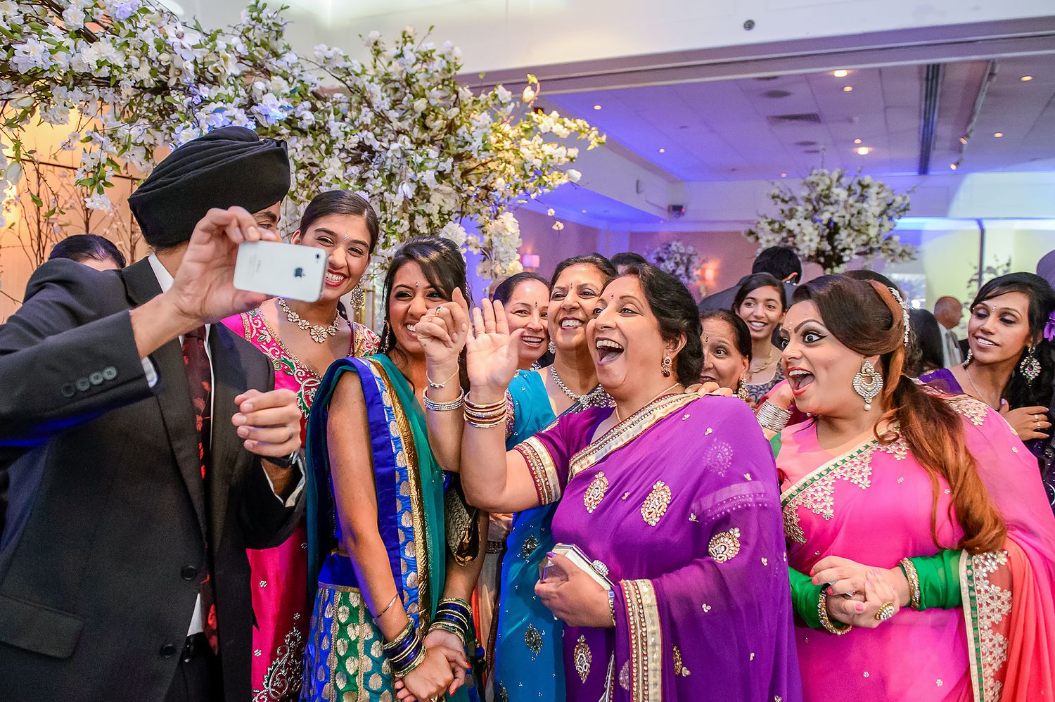 Joyful wedding celebration with guests in colorful saris sharing laughs together.