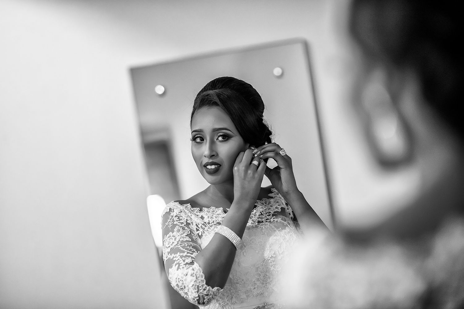 Wedding preparation scene shows delicate lace details in black and white photography.