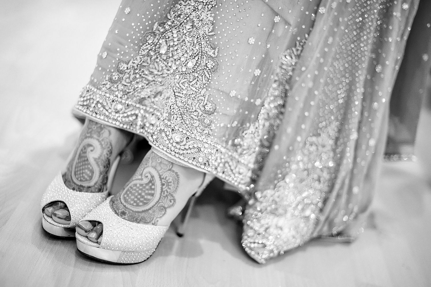 Ornate bridal shoes with detailed beadwork next to an embellished wedding dress hem.
