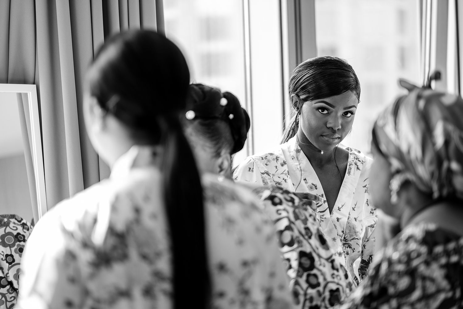 Wedding preparations captured through window reflections with floral robes.