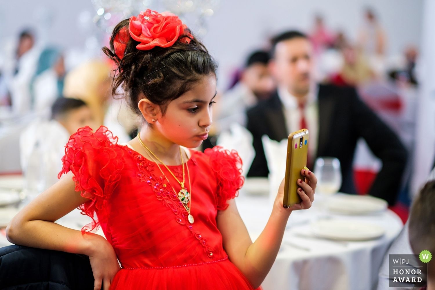 Child in bright red dress twirling on dance floor at wedding reception.