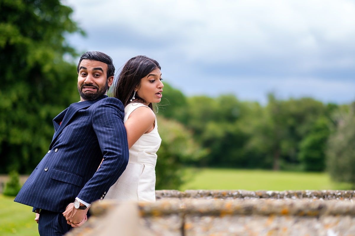 Wedding couple walks together on stone pathway surrounded by lush greenery.