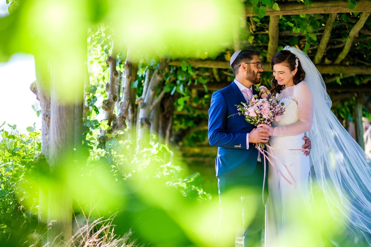 Romantic wedding ceremony captured through soft-focus greenery and natural light.