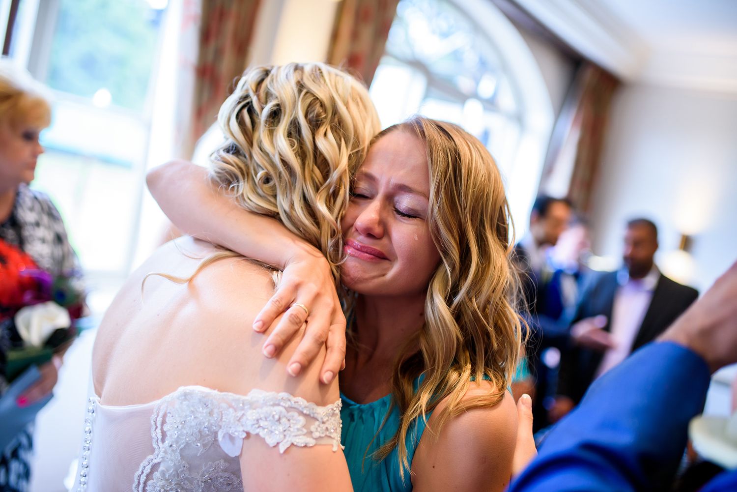 An emotional embrace between wedding guests shows a heartfelt moment during the celebration.