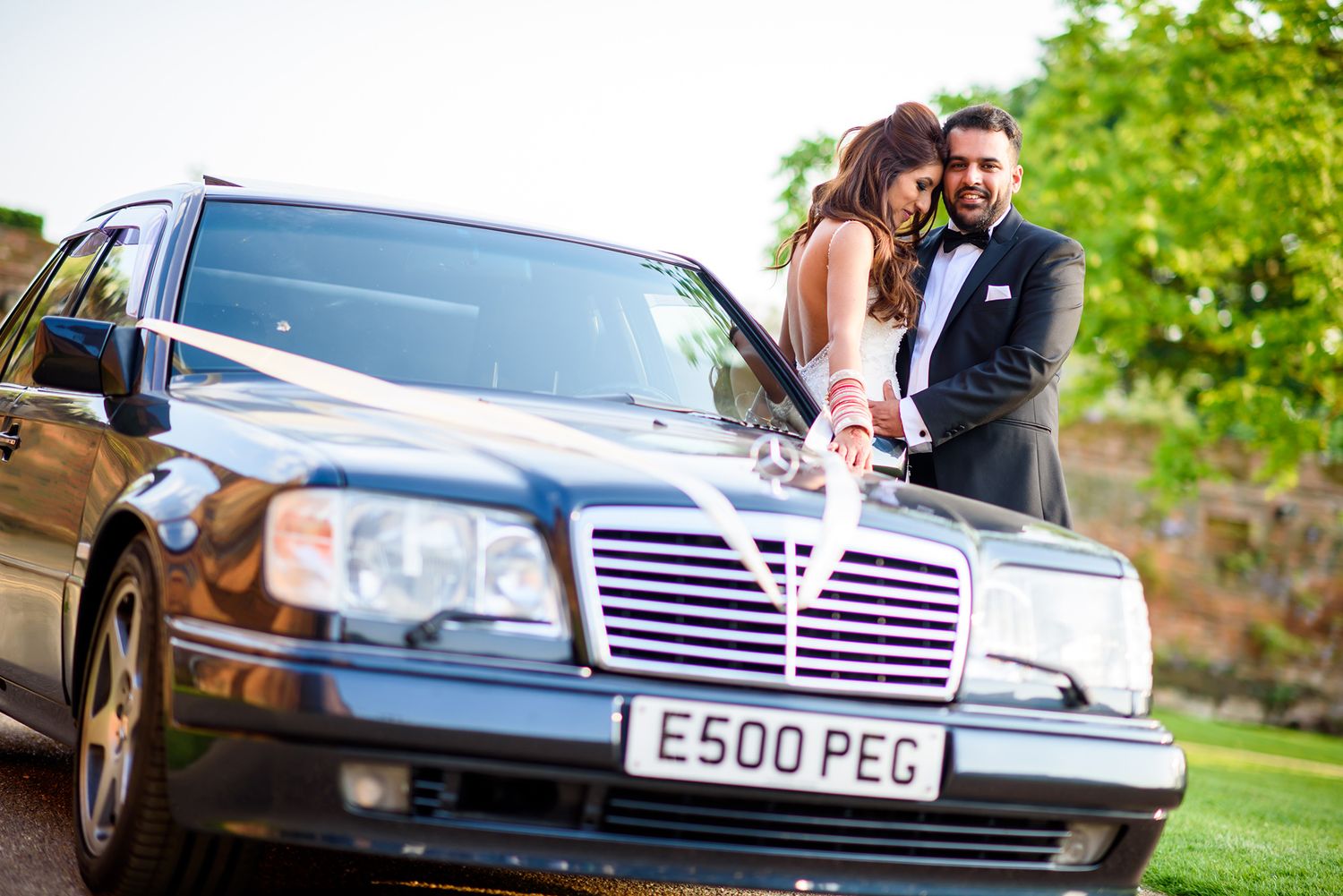 Luxury vintage wedding cars lined up with decorative ribbons and flags.
