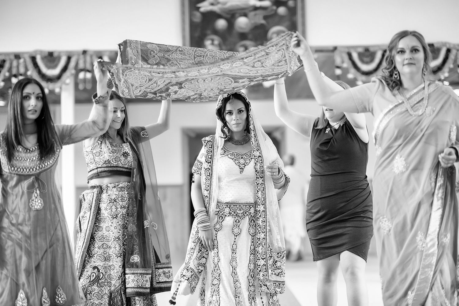 Wedding guests in colorful saris dancing and celebrating at an Indian reception.
