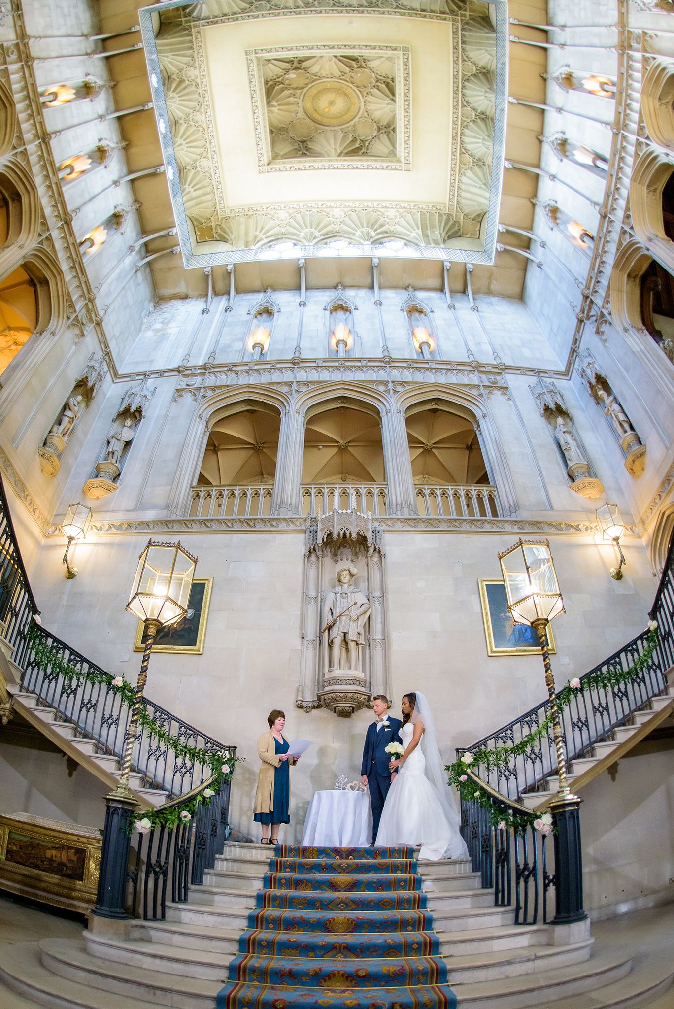 Elegant grand staircase in historic mansion with ornate white architecture and arched details.