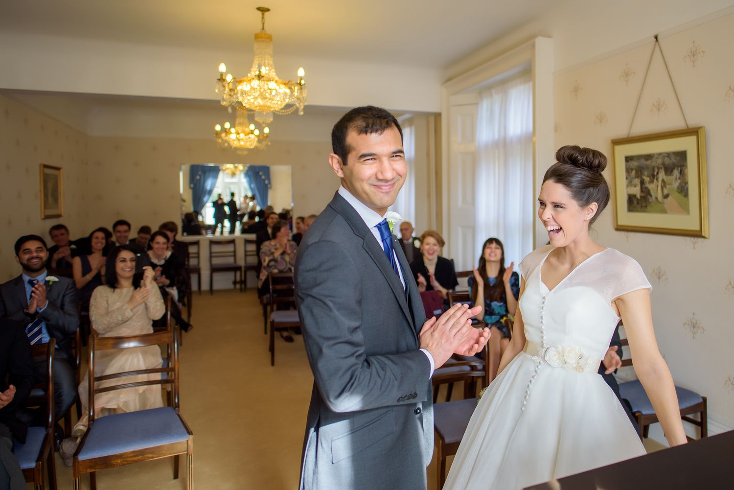 Wedding ceremony in a bright indoor venue with guests watching the couple exchange vows.