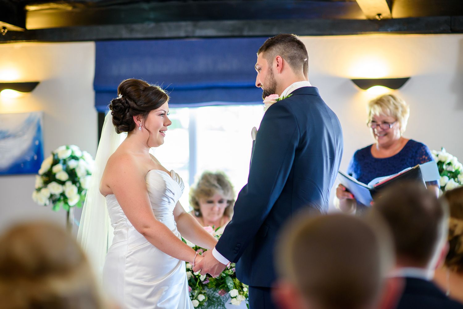 A tender moment during a wedding ceremony with guests watching in the background.