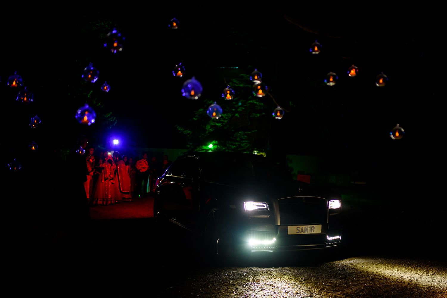 Nighttime outdoor celebration with car headlights illuminating the dark scene.