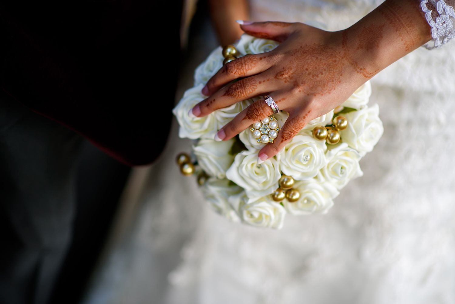 Beautiful white rose wedding bouquet held against lace dress.