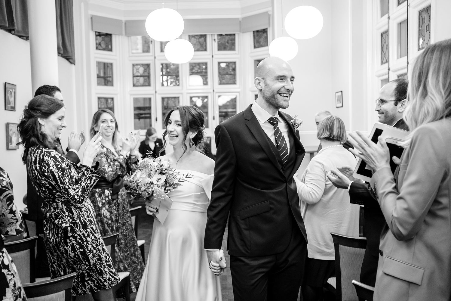 Wedding celebration in a bright venue with ornate windows and elegant decor.