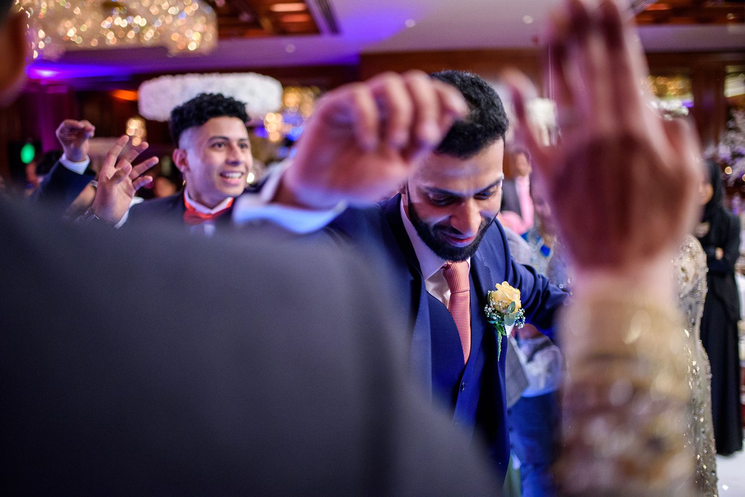 Wedding celebration at an indoor venue with colorful purple lighting and festive atmosphere.