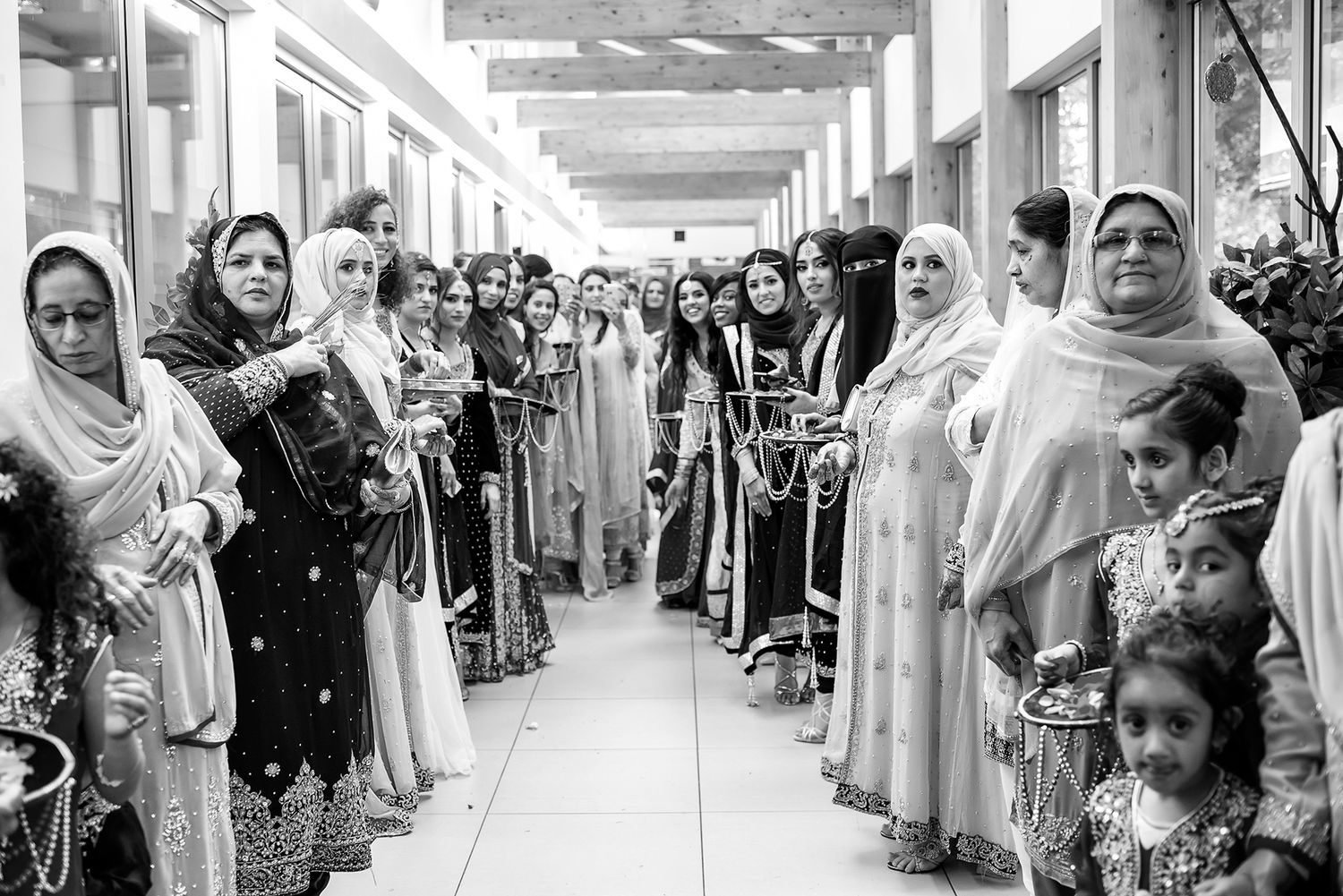 Long corridor filled with wedding guests in traditional dress during celebration.