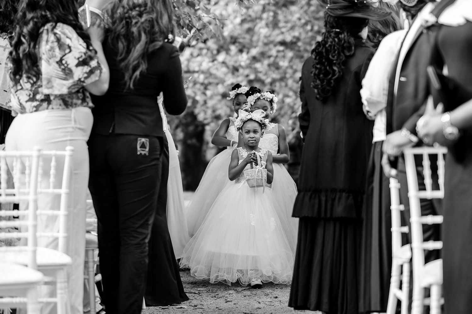 Wedding ceremony setup with white chairs and floral arrangements in an outdoor garden.