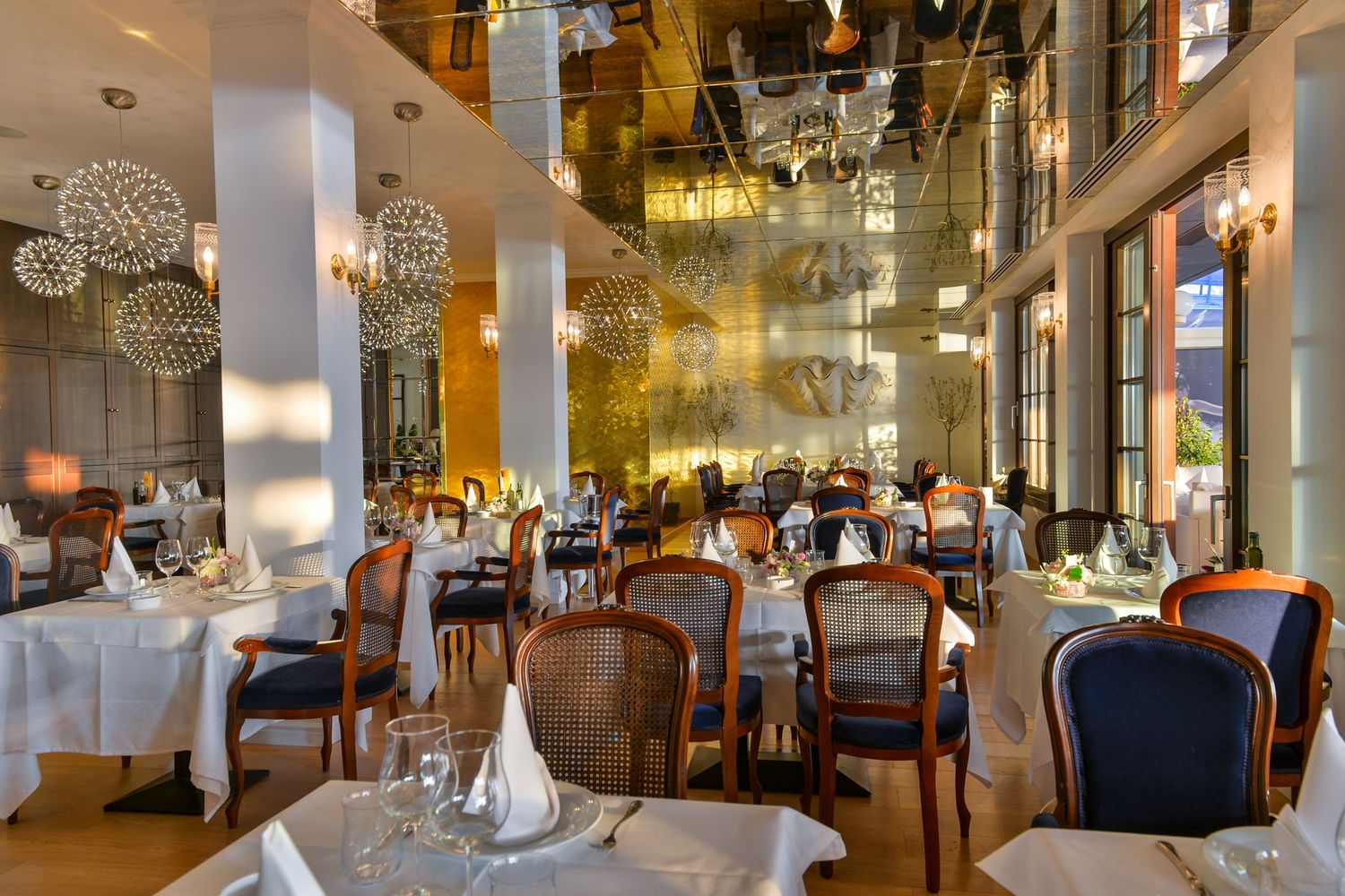 Luxurious restaurant dining room with crystal chandeliers and formal table settings.