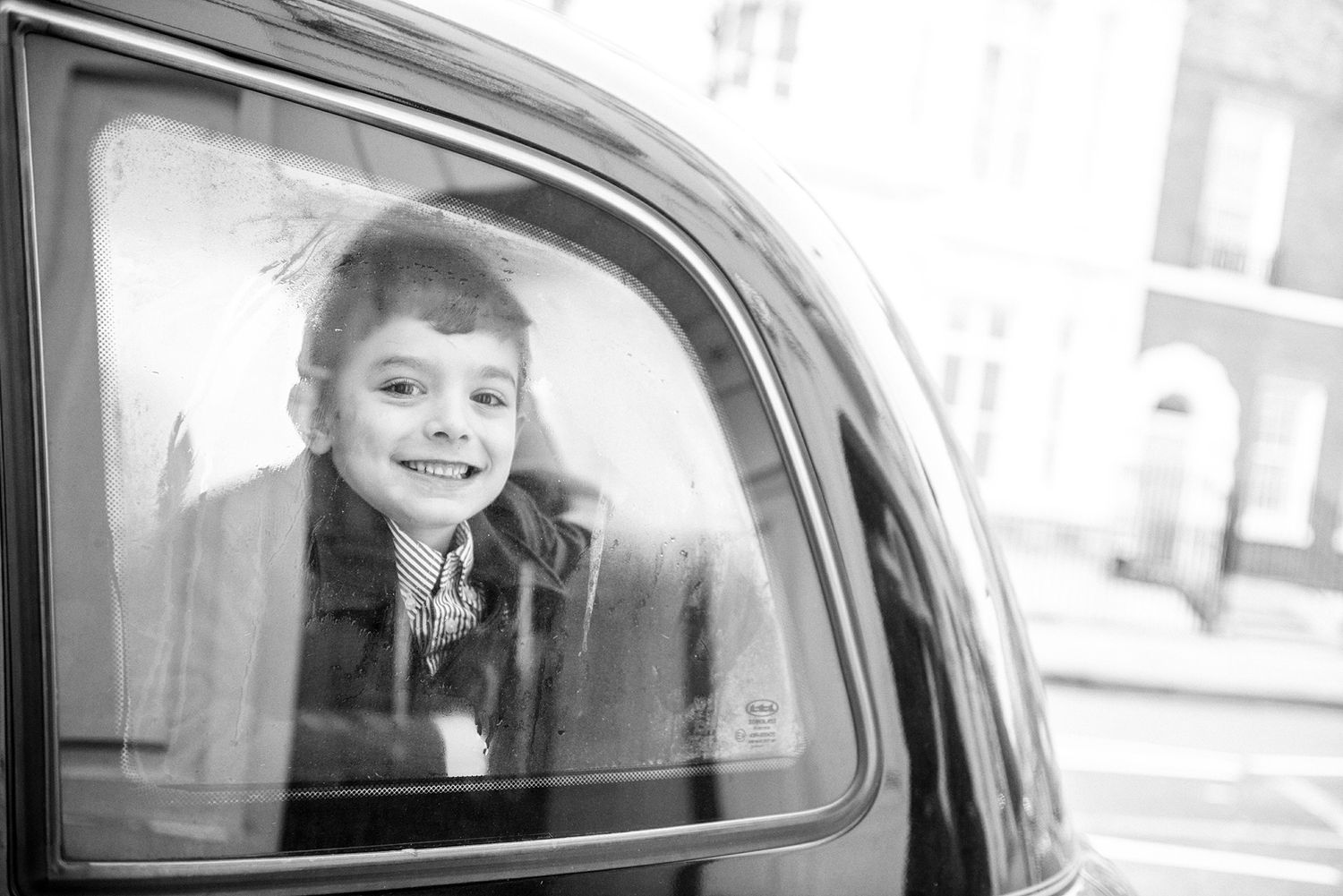 Black and white images of children looking out of vintage car windows.