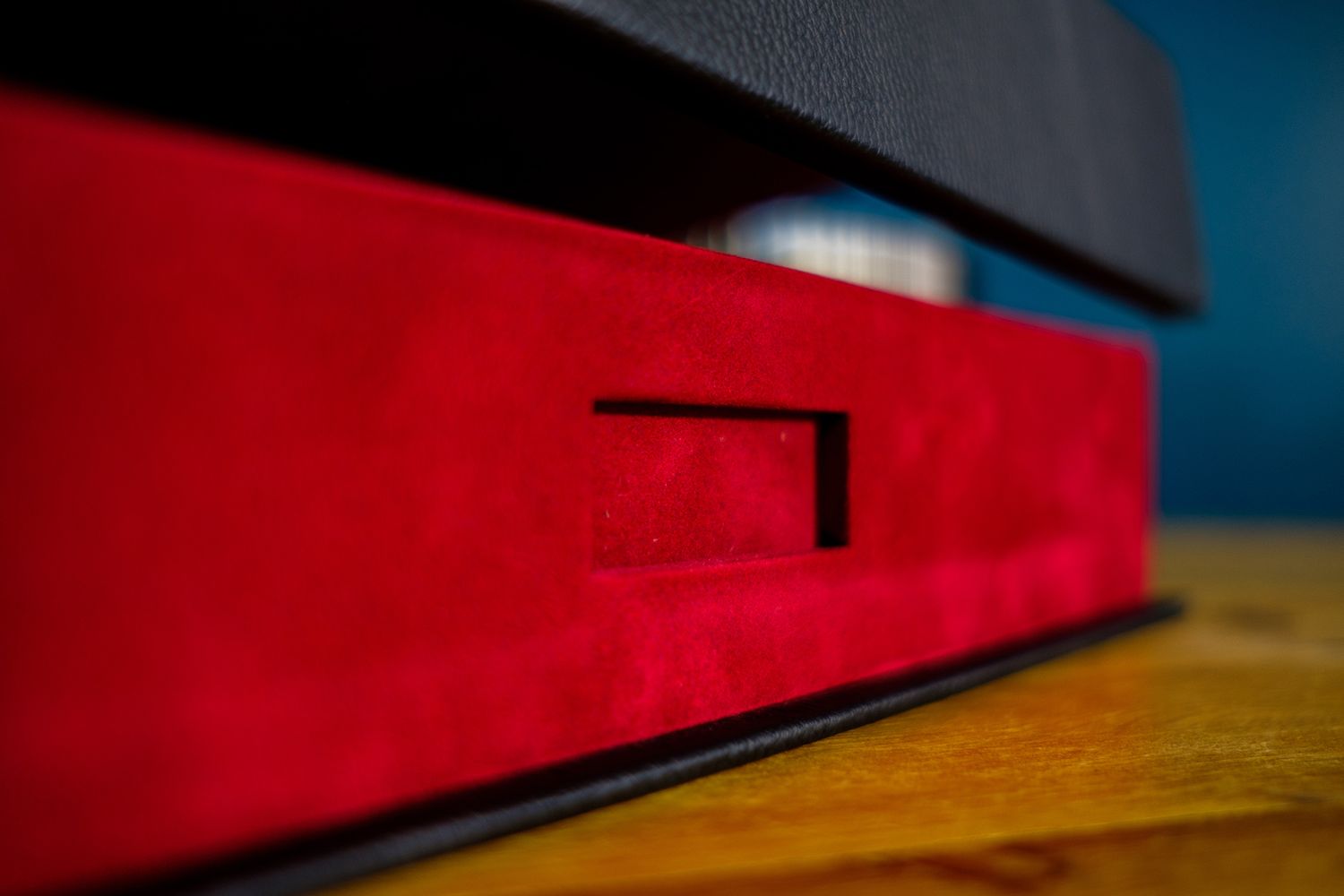 Red and black photo album displayed with dramatic side lighting on wooden surface.
