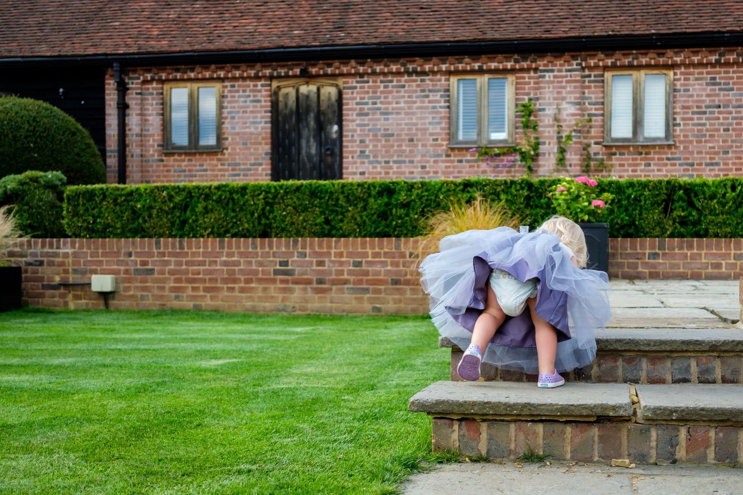 Exterior view of a brick wedding venue with manicured lawn and garden.