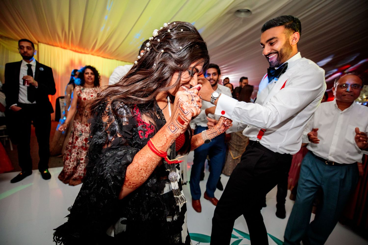 Dynamic dance floor moments captured during evening wedding reception celebrations.