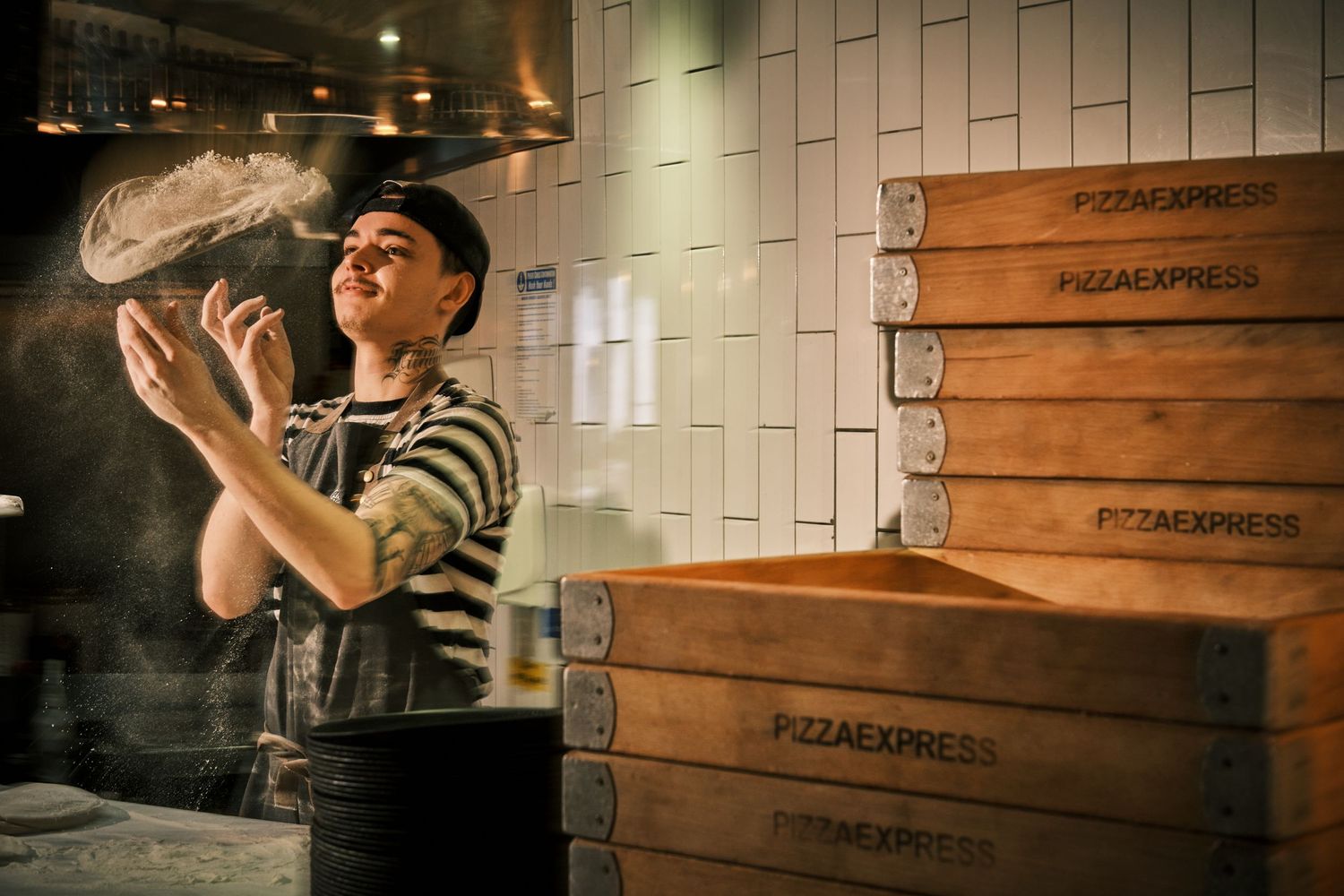 Professional chef preparing food in modern industrial kitchen with wooden wall panels.