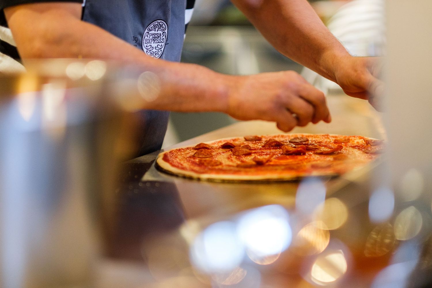 Hands serving freshly baked pizzas on wooden boards in a restaurant setting.