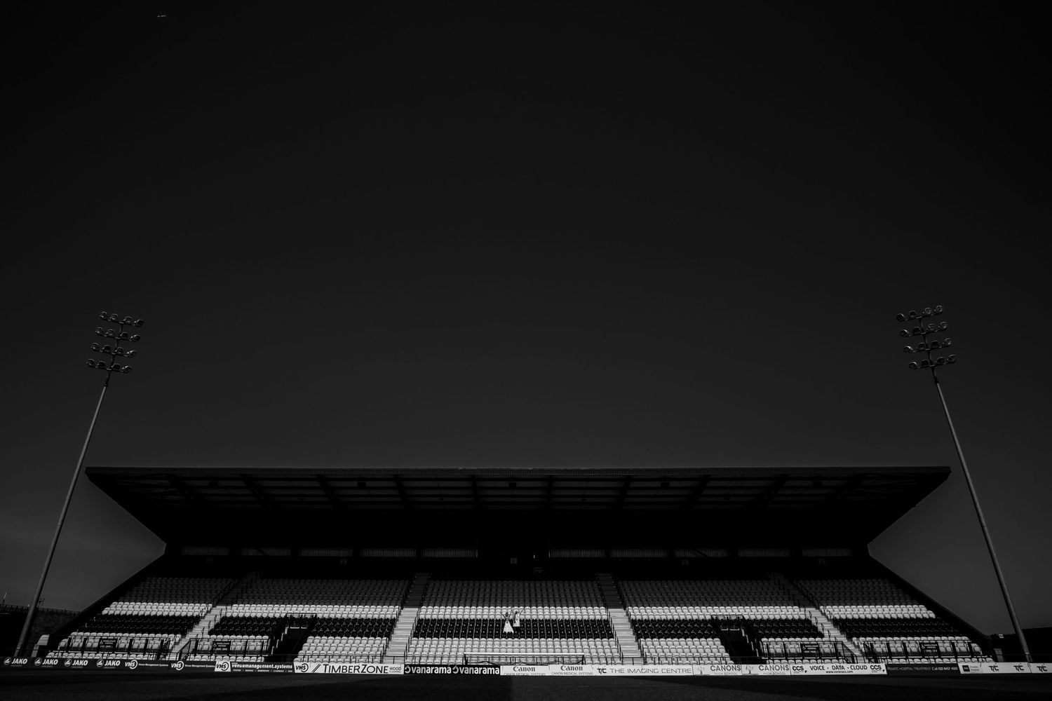 Silhouette of a sports stadium against a dark sky with floodlights visible.