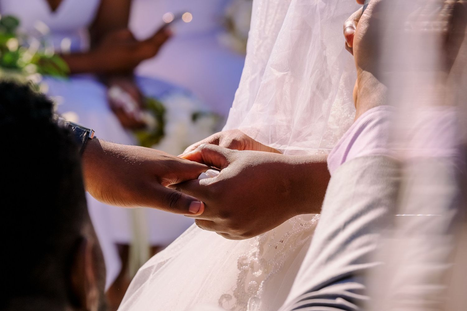 Wedding ceremony moments captured showing hands exchanging rings during the service.