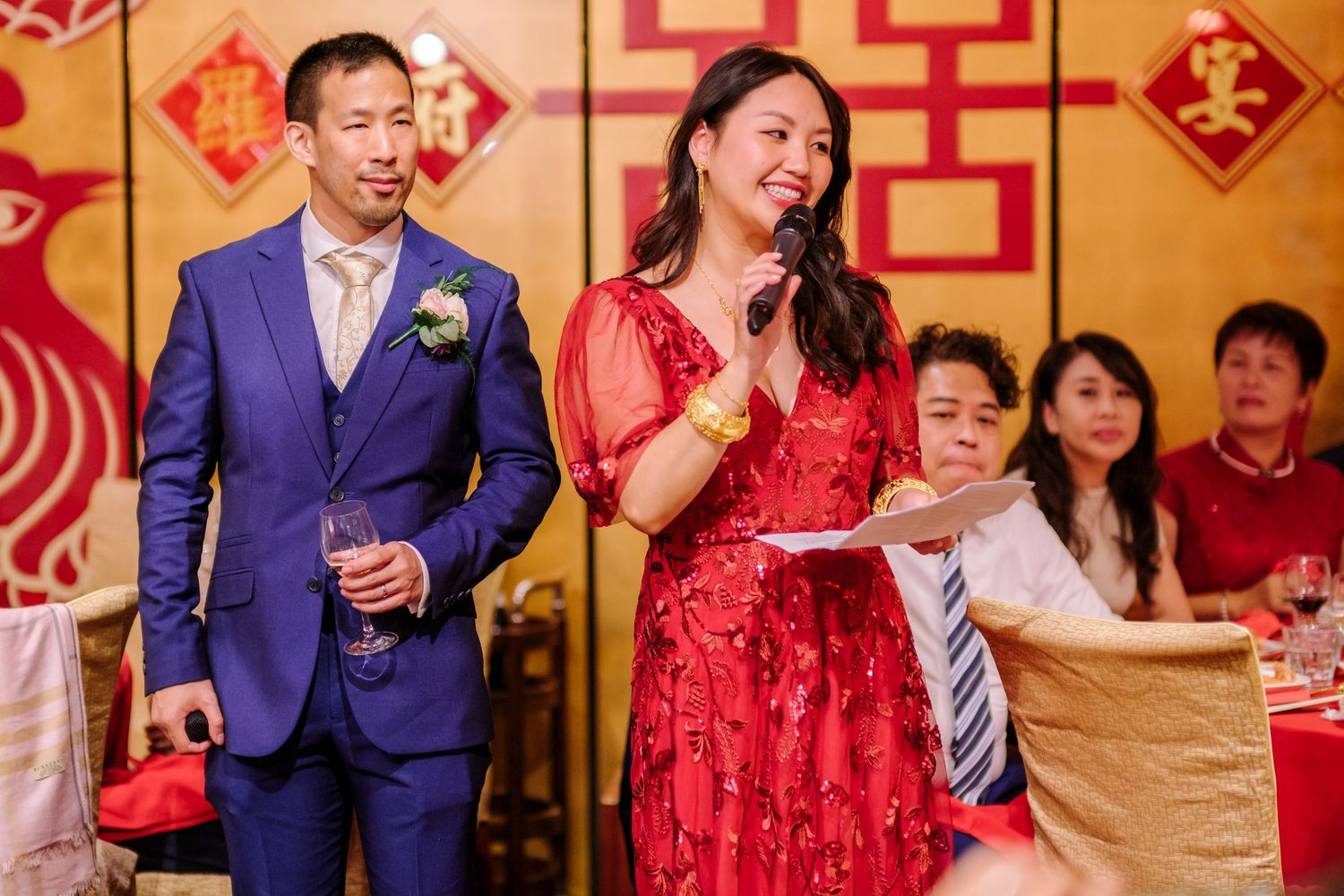 Wedding reception in a banquet hall decorated with red and gold Chinese traditional elements.