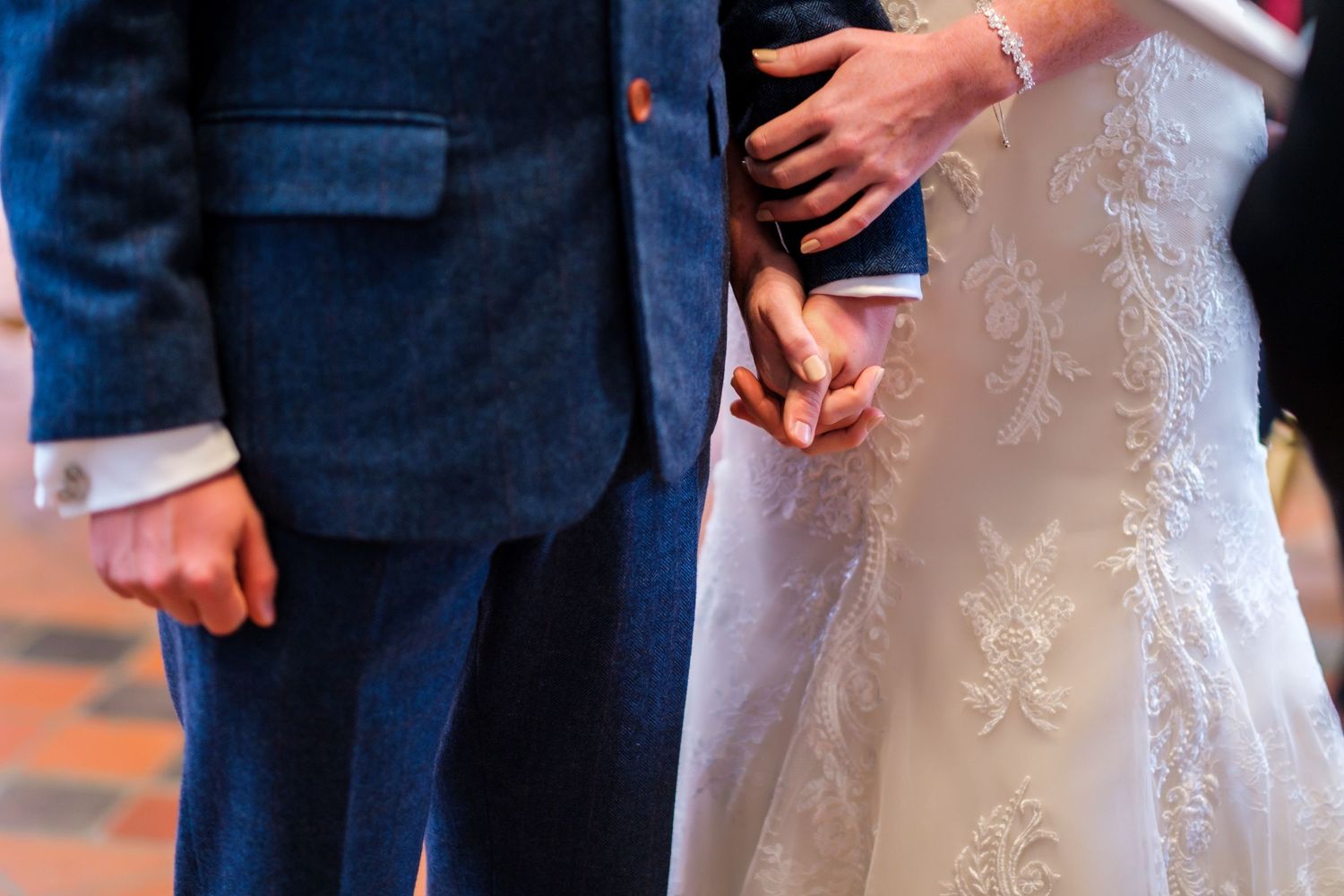 Close-up of elegant white lace wedding dress details during ceremony.