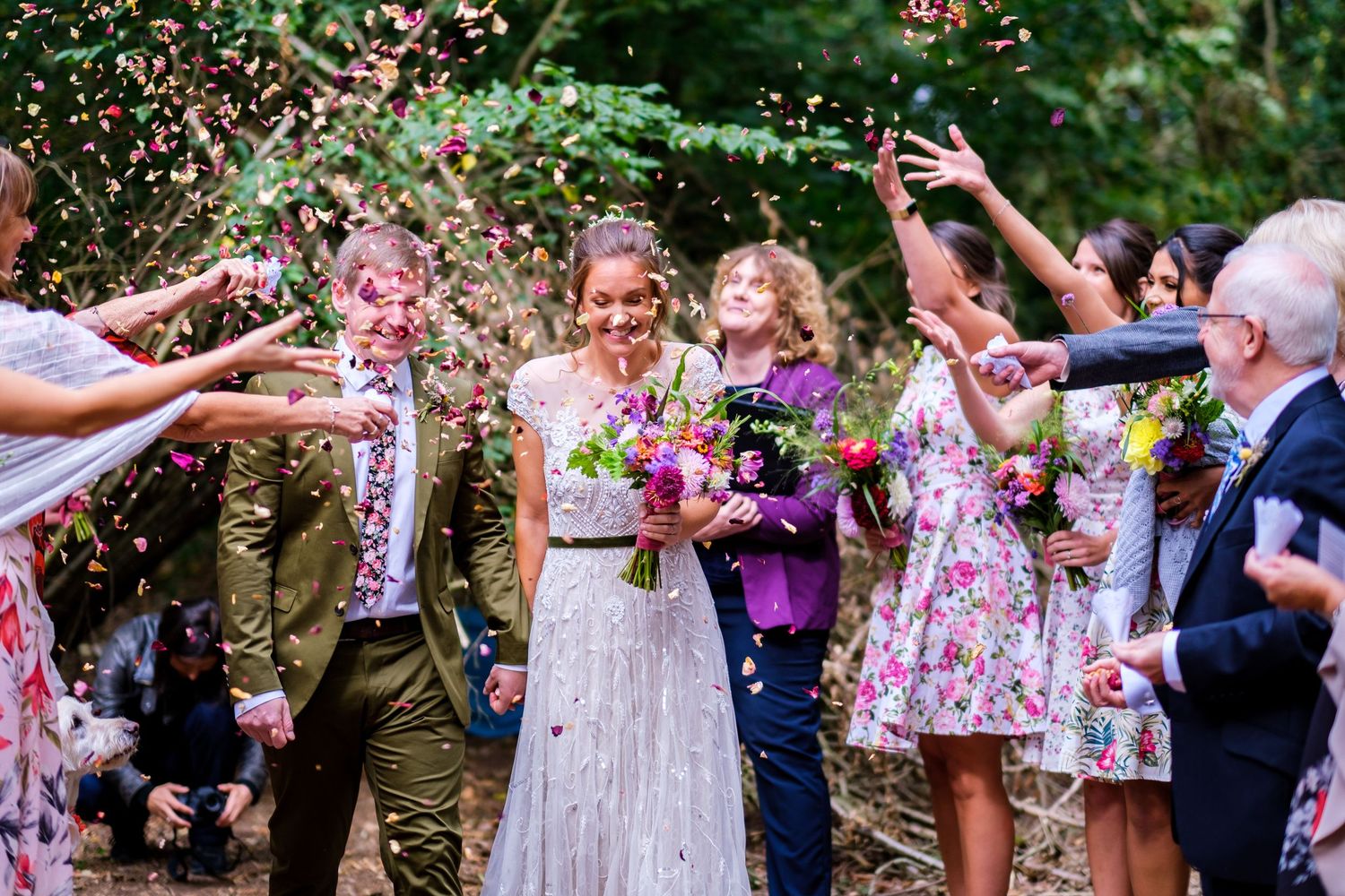 Joyful celebration with confetti being thrown during an outdoor forest wedding.
