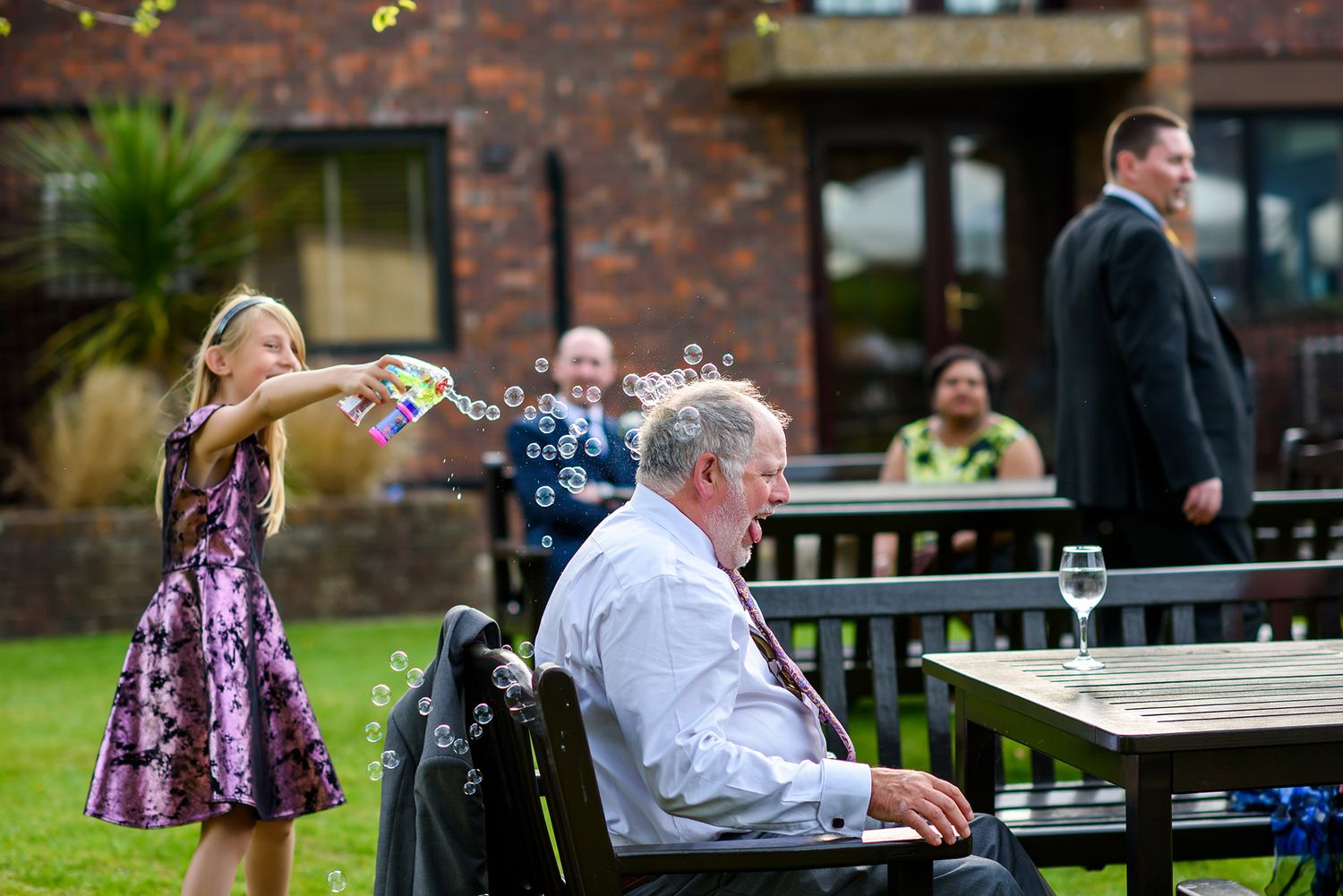 Guests enjoy refreshments at outdoor tables during a brick venue reception.