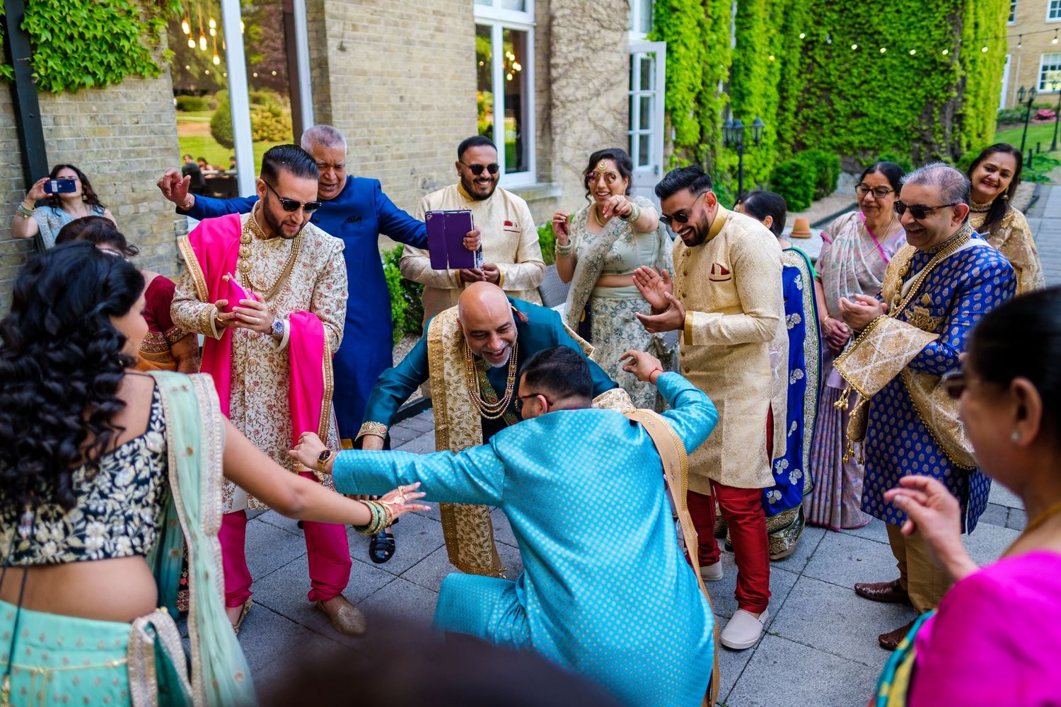 Energetic dance celebration with guests in colorful traditional Indian attire at outdoor venue.
