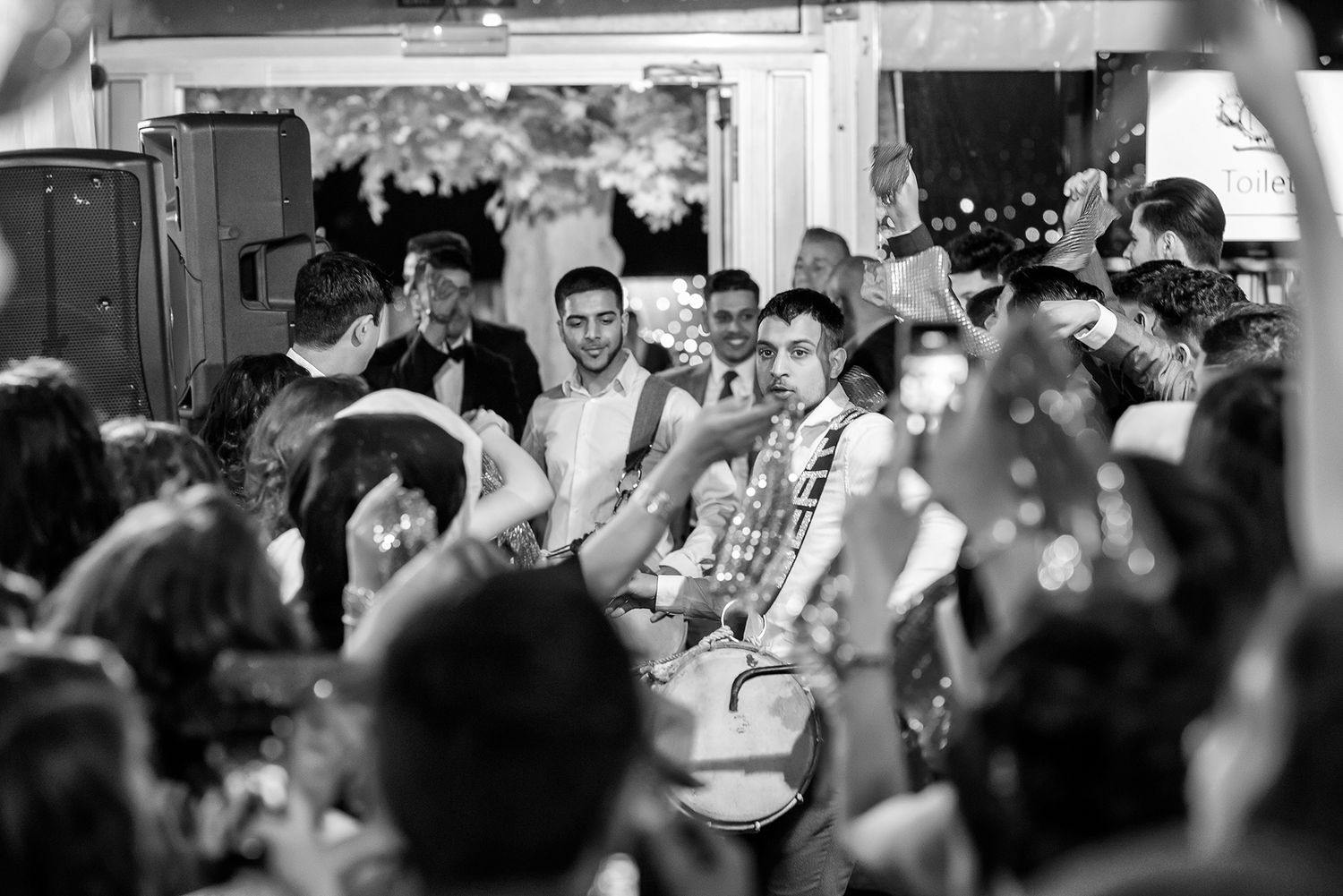 Black and white photo of crowd celebrating at wedding reception.