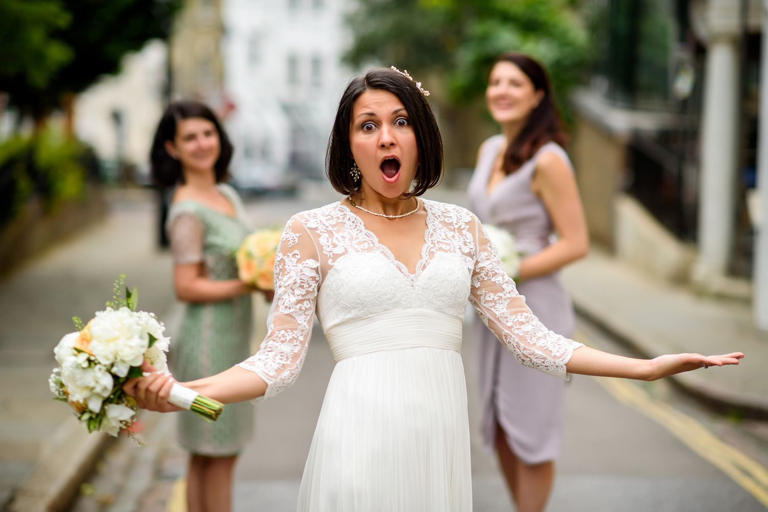 Wedding group creates energetic action shot on quaint city street.