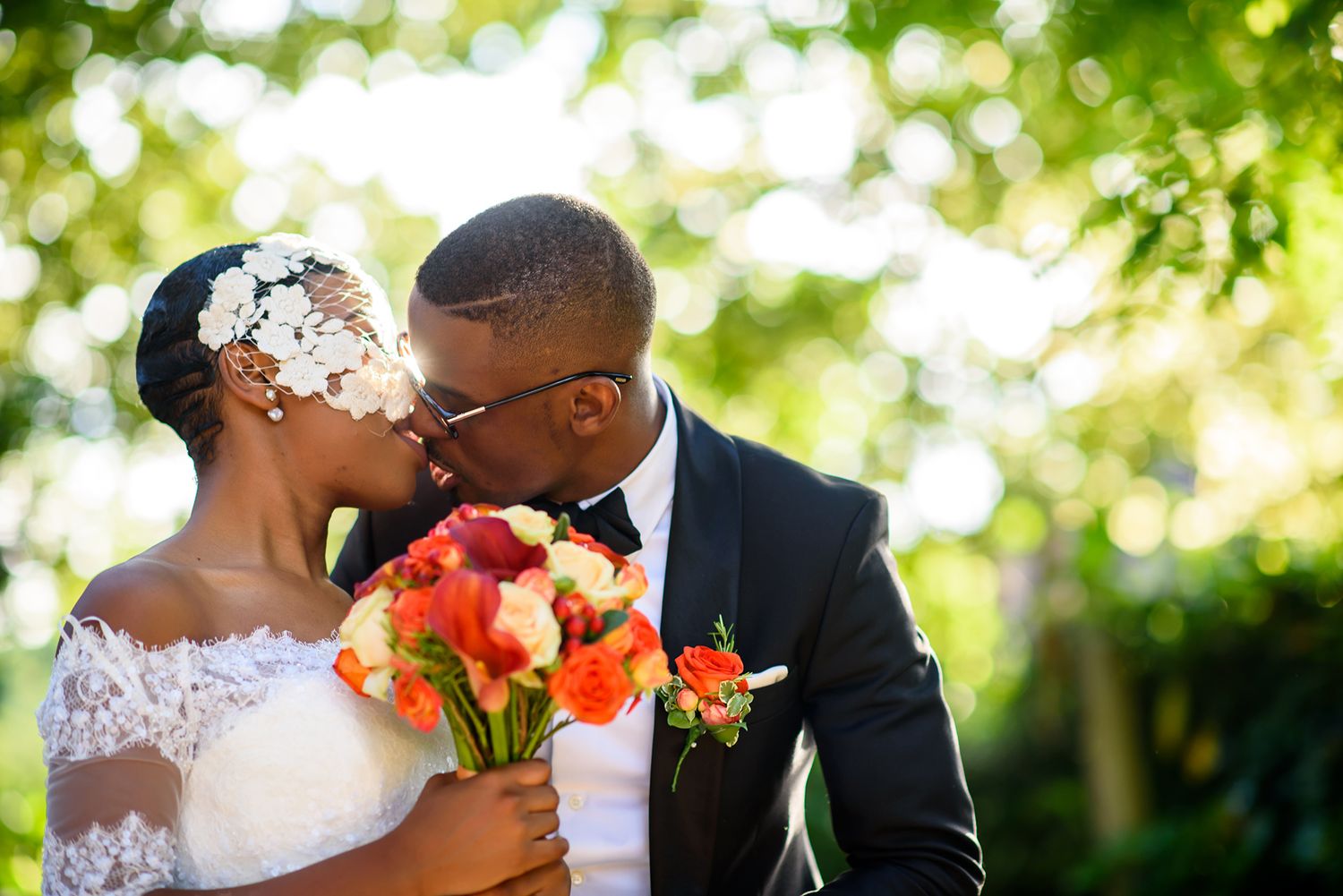 Wedding celebration in a lush garden setting with orange floral bouquet accents.