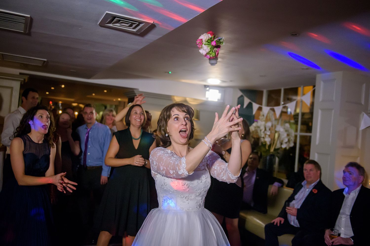 Wedding reception dance floor filled with guests celebrating under ambient lighting.
