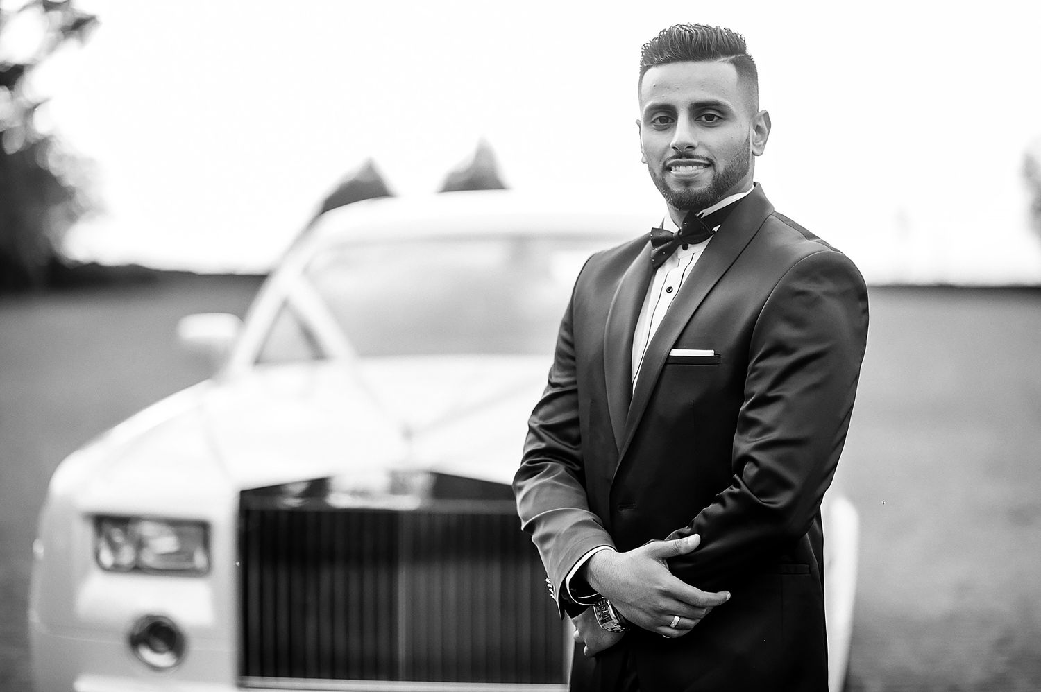 Black and white portrait with luxury car in background.