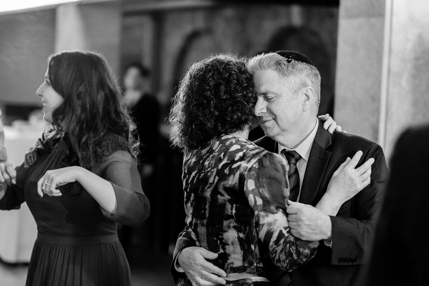 Wedding guests dancing and celebrating on a dimly lit dance floor.