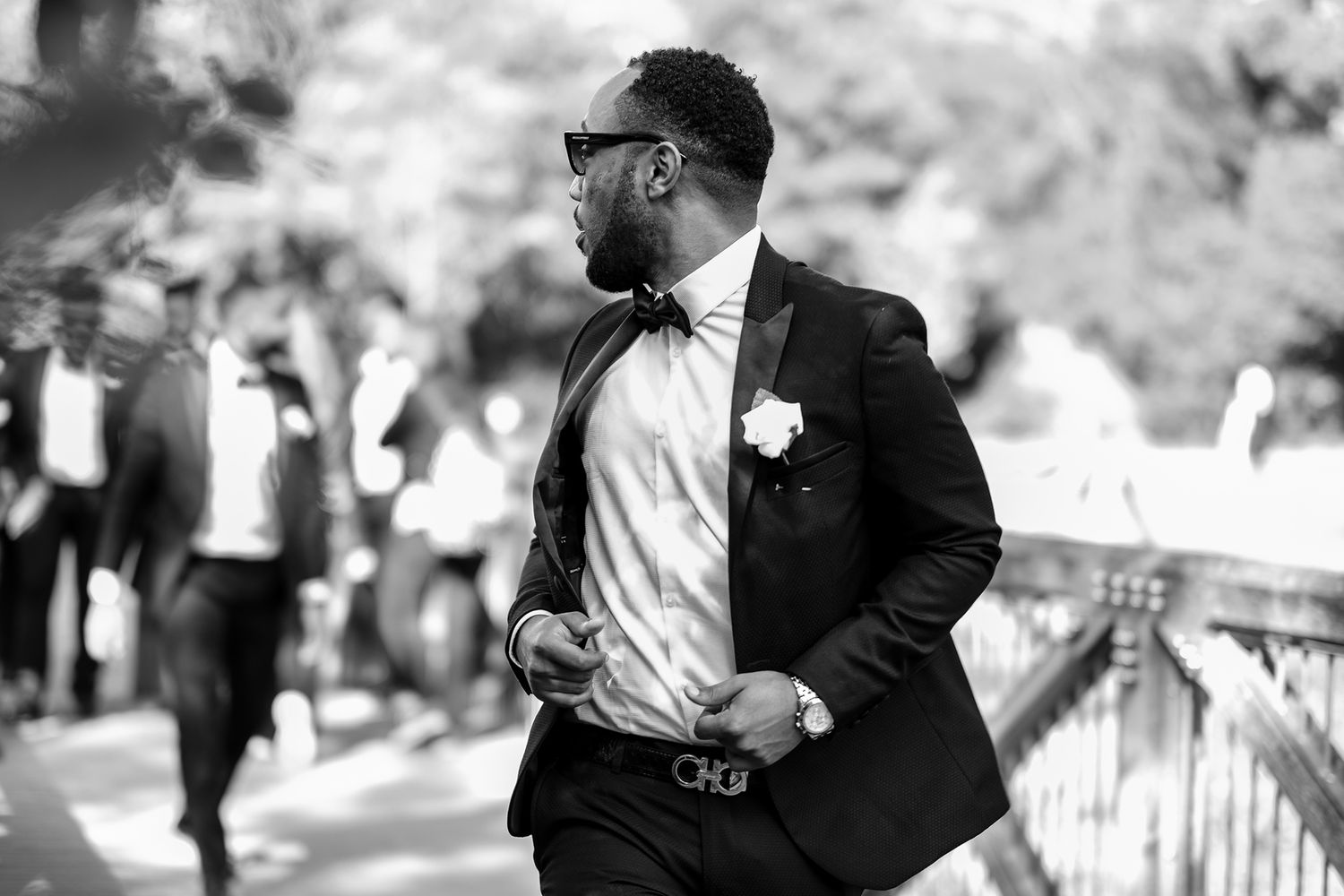 Wedding party in formal attire walking together outdoors on a sunny day.