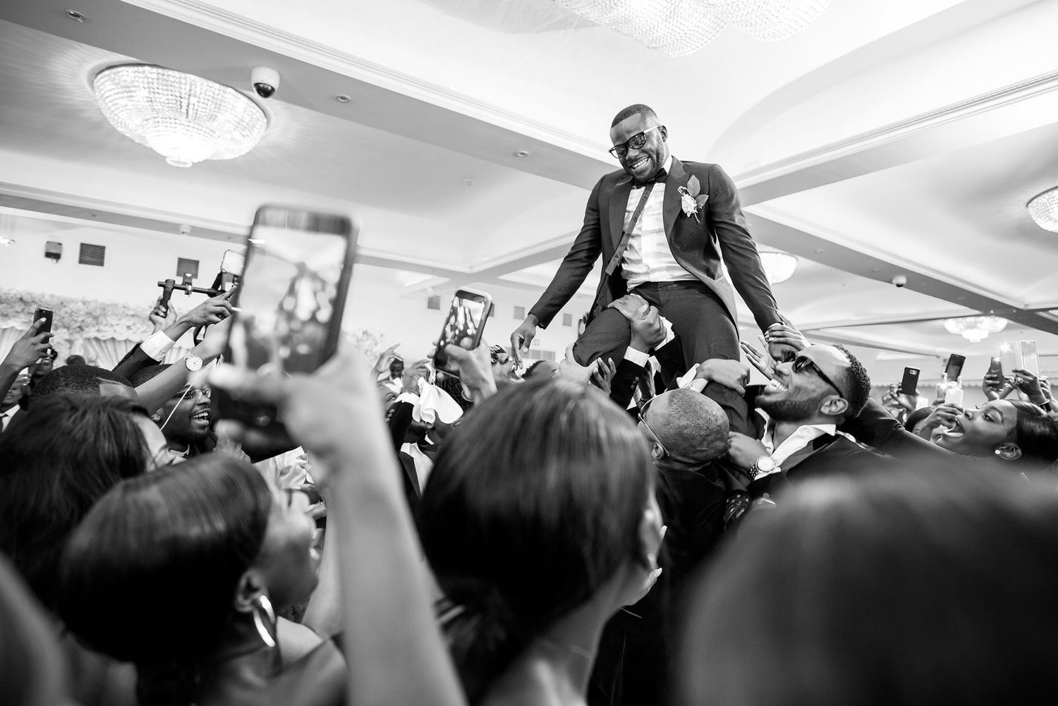 Guest being lifted up by crowd during lively wedding reception celebration.