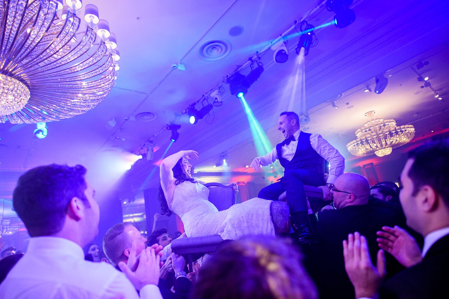 Nightclub atmosphere with purple and blue lighting effects over a crowded celebration.